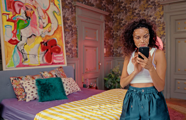 Blonďat&aacute; žena zabalen&aacute; do ručn&iacute;ku sed&iacute; před zrcadlem.