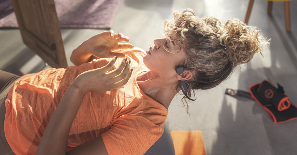 Sportovec použ&iacute;vaj&iacute;c&iacute; sluch&aacute;tka s otevřen&yacute;m uchem při vnitřn&iacute;m cvičen&iacute;