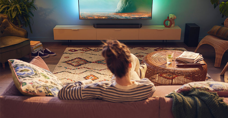 Žena si už&iacute;v&aacute; svůj Philips Soundbar v ob&yacute;vac&iacute;m pokoji