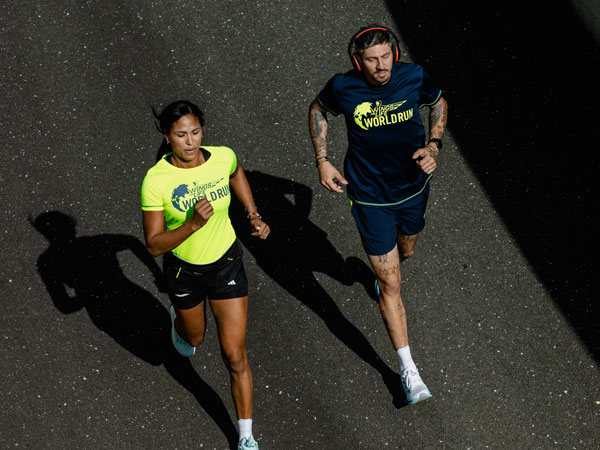 Dva běžci snaž&iacute;c&iacute; se udržet před st&iacute;hac&iacute;m vozem.